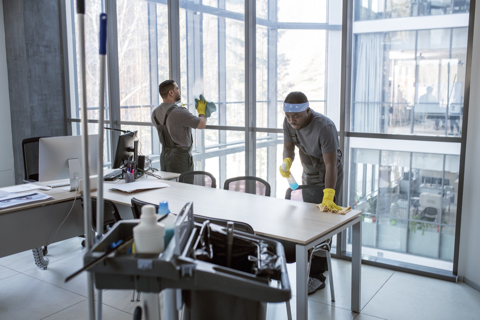 Two cleaning operatives in yellow gloves carrying out a detailed office clean